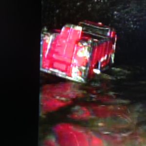 Red toy fire truck submerged in water, highlighting plumbing issue caused by child flushing toy down toilet.