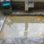 Clogged kitchen sink with stagnant water and debris, highlighting the importance of using drain screens to prevent plumbing issues.
